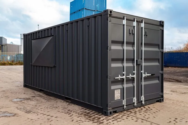 Dark grey converted container with a shuttered side opening and cargo doors